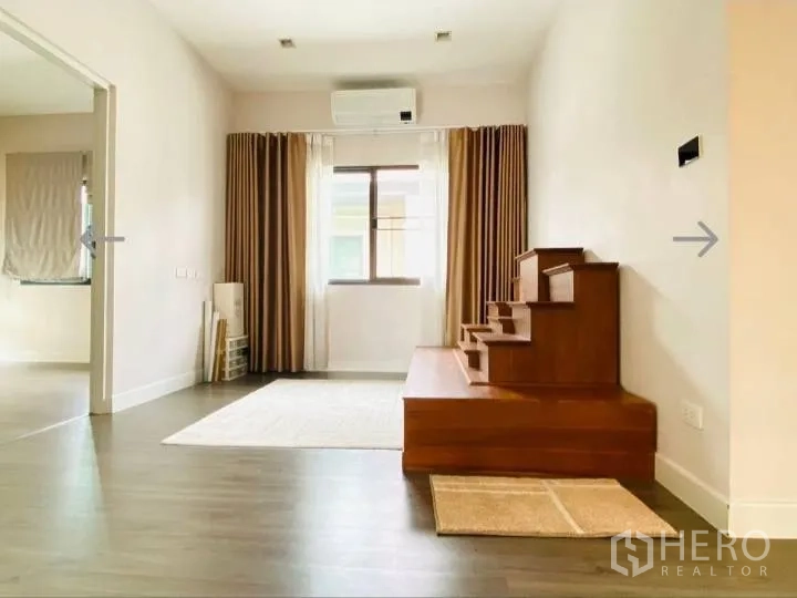 Detached House for sale in Saphan Sung, Bangkok - Upper living area with wood platform steps, curtains and a window.
