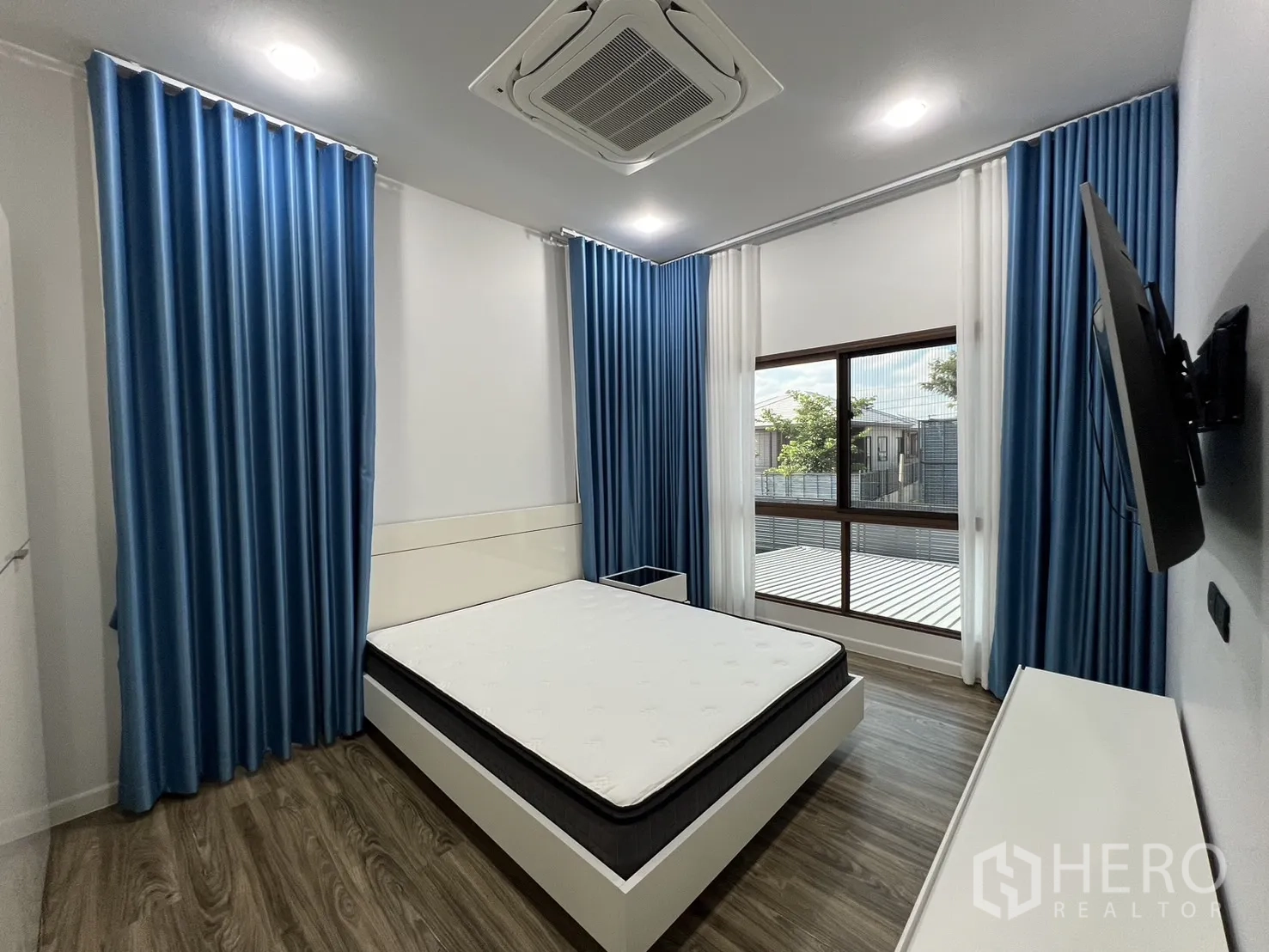 Detached House for rent or sale in Bang Kapi, Bangkok - Guest bedroom with blue curtains, white furniture and wall-mounted TV