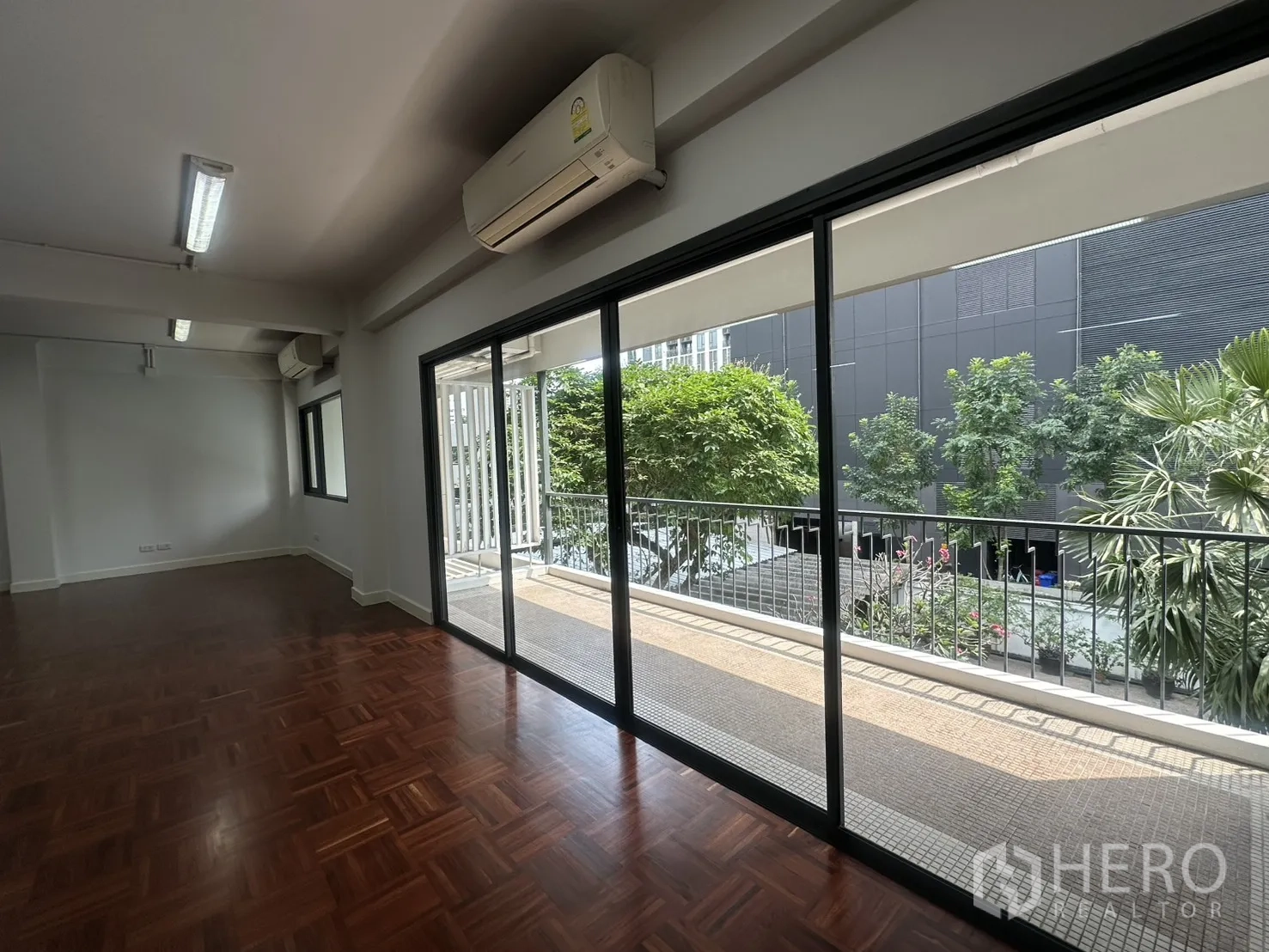 ออฟฟิศ for rent in Watthana, Bangkok - ประตูกระจกเปิดสู่ระเบียง มองเห็นแนวต้นไม้และอาคารสมัยใหม่
