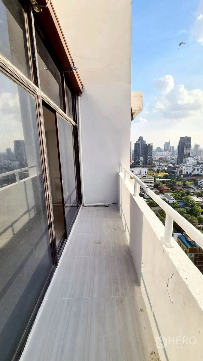 Condominium for rent in Watthana, Bangkok - Narrow balcony with railing and city view beside sliding glass doors.