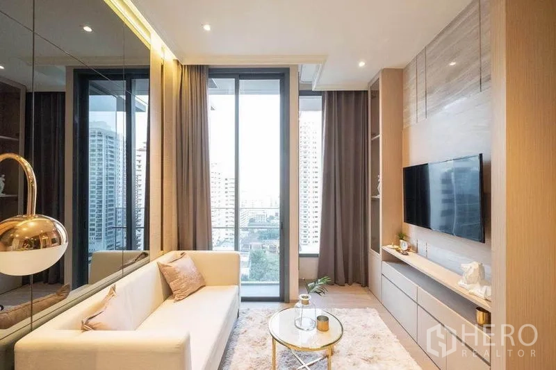 Condominium for rent in Watthana, Bangkok - Living area with built-in TV wall, balcony doors and full-height curtains.