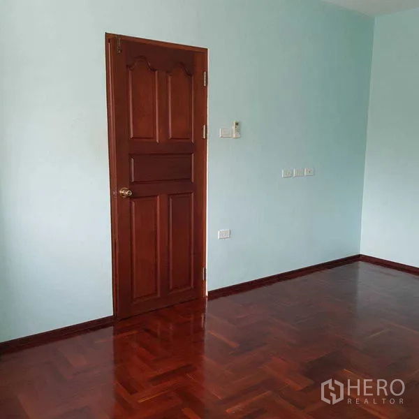 Home Office for rent in Watthana, Bangkok - Empty room with polished parquet floor and wooden door.