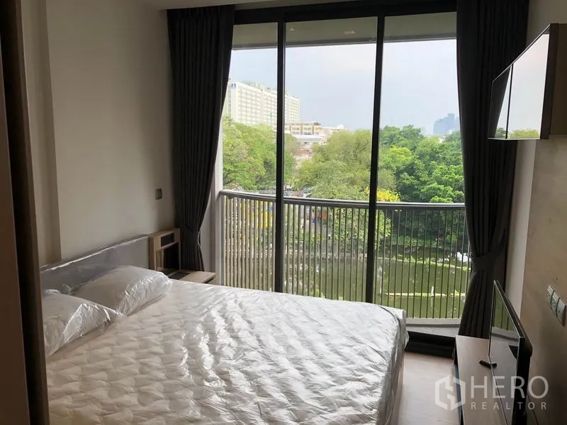 คอนโด ให้เช่าในWatthana, Bangkok - ห้องนอนเตียงคู่ เปิดสู่ระเบียงชมวิวคลองและต้นไม้ มีทีวีกับผ้าม่านทึบ