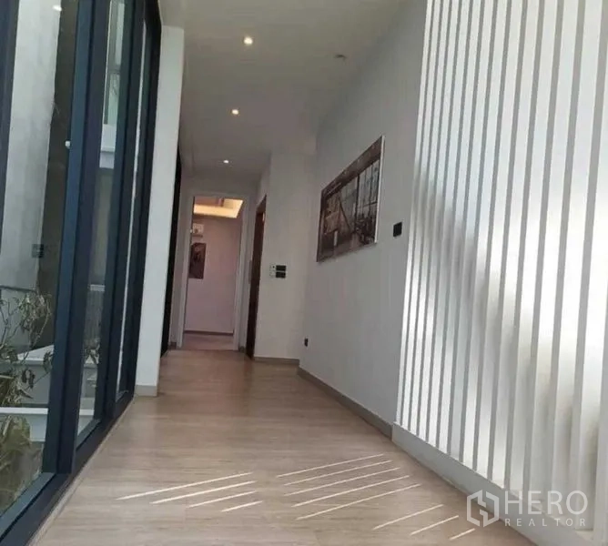 Home Office for rent in Suan Luang, Bangkok - Bright corridor with wood flooring, vertical white slats and floor-to-ceiling windows.
