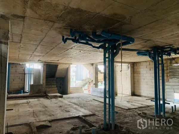 Home Office for rent - Raw interior floor with exposed blue plumbing pipes and a concrete ceiling.