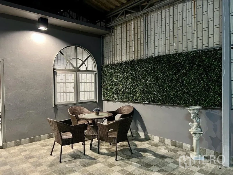 Shophouse for sale in Bang Kho Laem, Bangkok - Covered patio with rattan dining set and green wall.