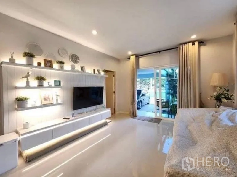 Detached House for rent in Bang Bo, Samut Prakan - Spacious lounge with TV wall and sliding doors opening to the carport and patio.