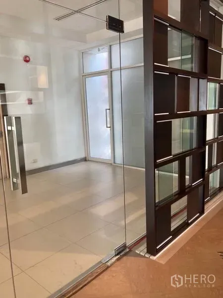 Office Space for rent in Khlong Toei, Bangkok - Glass-walled office entry with frosted door, tiled floor and modern grid partition.