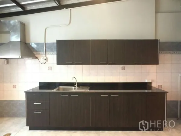 Townhouse for rent in Khlong Toei, Bangkok - Fitted kitchen with dark cabinetry, black countertops, sink, and stainless steel range hood.