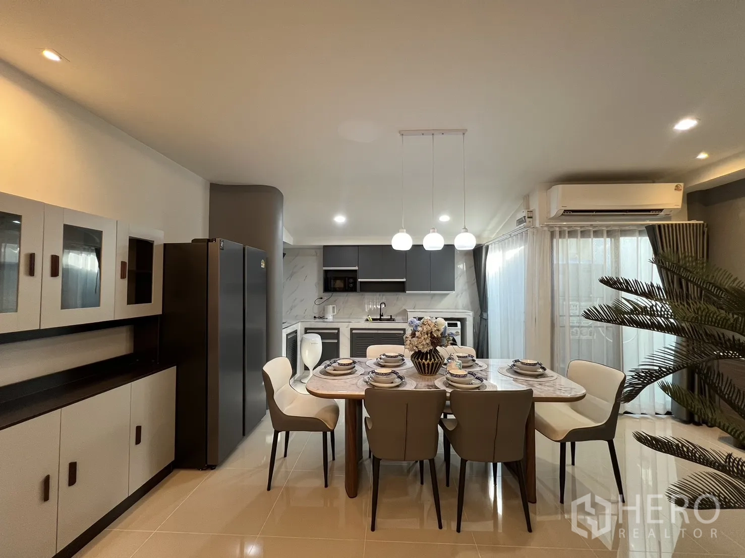 Townhouse for rent in Bang Phli, Samut Prakan - Spacious kitchen-dining area with grey cabinets, pendant lamps and AC unit.