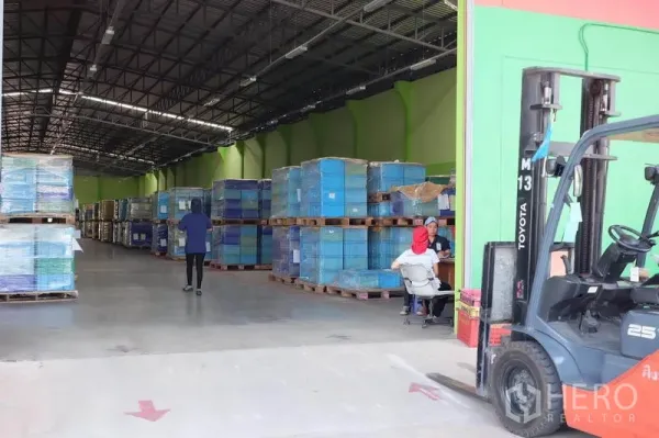 货栈 出租在Ban Phaeo, Samut Sakhon - 装卸口处的叉车，旁有缠膜托盘，内部通道宽敞明亮。