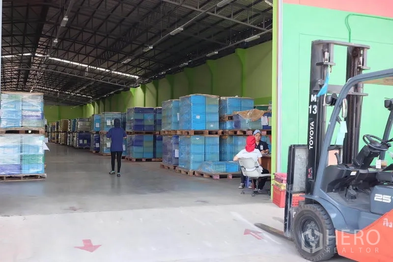 货栈 出租在Ban Phaeo, Samut Sakhon - 装卸口处的叉车，旁有缠膜托盘，内部通道宽敞明亮。