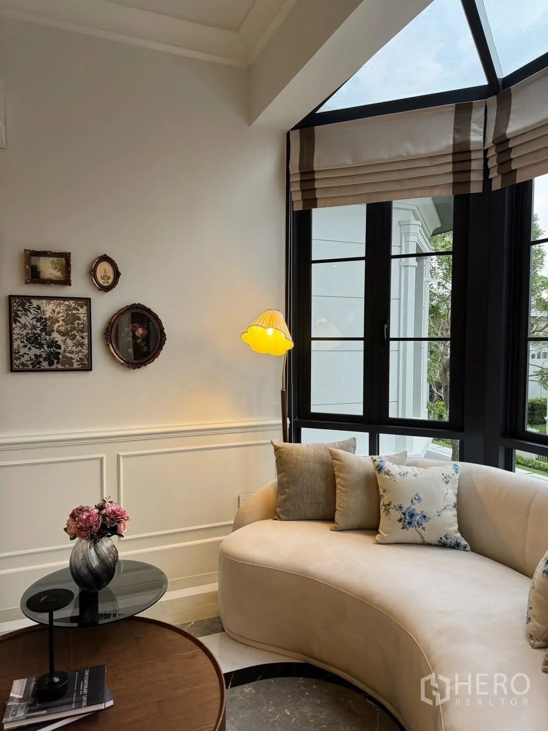 独立式住宅 出租在Bang Kapi, Bangkok - 凸窗边的弧形沙发角，墙面装饰画与台灯