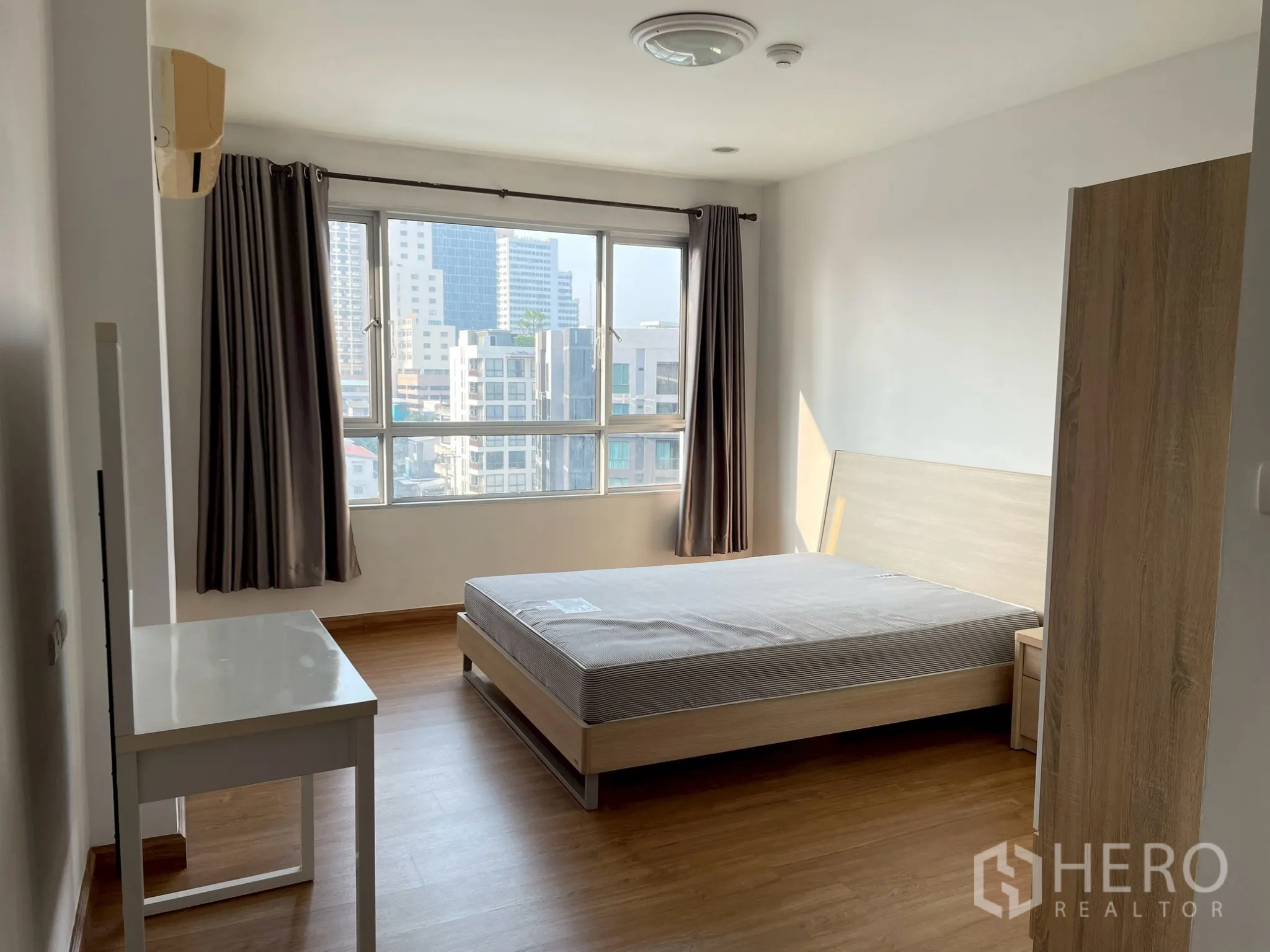 Apartment for rent in Khlong Toei, Bangkok - Bright bedroom with bed, big window, and cityscape outlook.