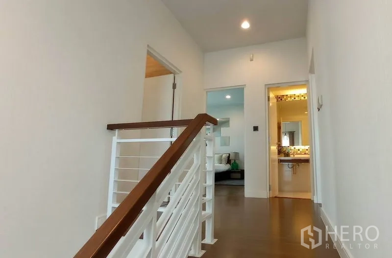 Detached House for rent in Bang Kapi, Bangkok - Upstairs landing with white railing leading to bedrooms and a bathroom.
