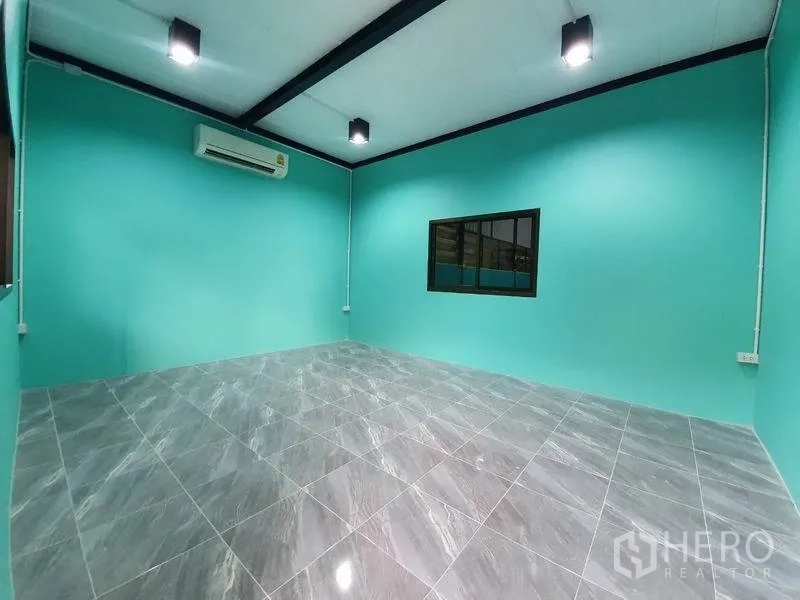 Warehouse for rent in Nonthaburi - Air-conditioned office room with teal walls, glossy gray floor tiles and an interior window to the warehouse.