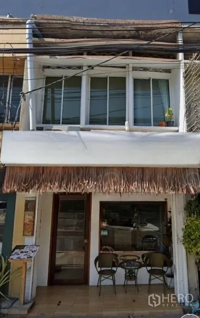 店屋 出租在Watthana, Bangkok - 位于Ekkamai的两层商铺外立面，玻璃门、阳台窗和街边小座位区。