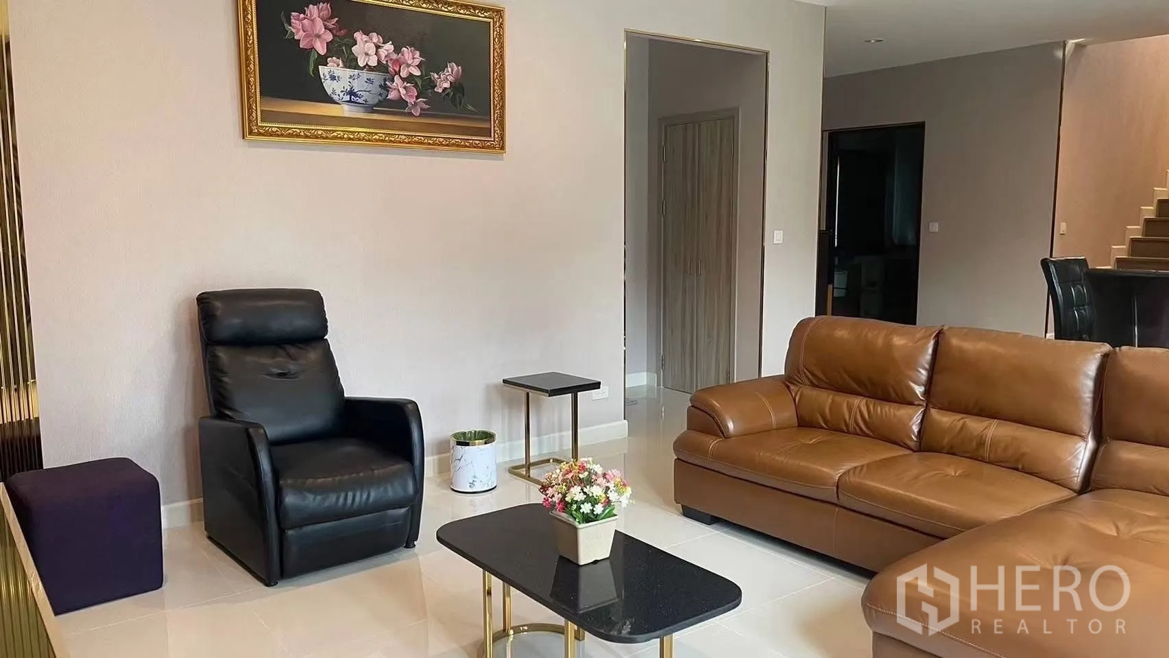 Detached House for rent in Prawet, Bangkok - Living room with brown leather sofa, black recliner and coffee table.