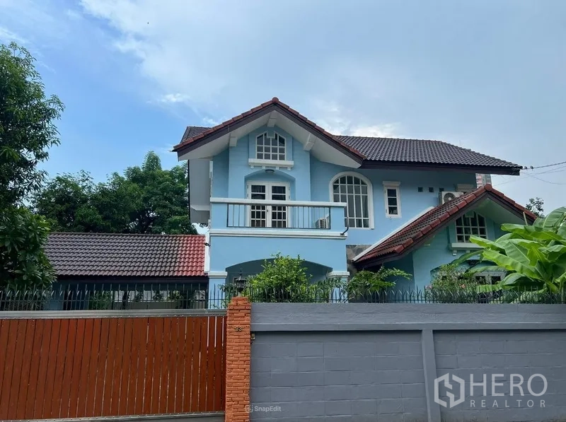 Detached House for rent in Bang Na, Bangkok - Close-up of the blue two-storey house with white balcony and arched windows