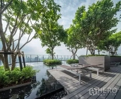 Condominium for rent in Watthana, Bangkok - Rooftop sky garden deck with benches, water feature, trees and panoramic skyline views.