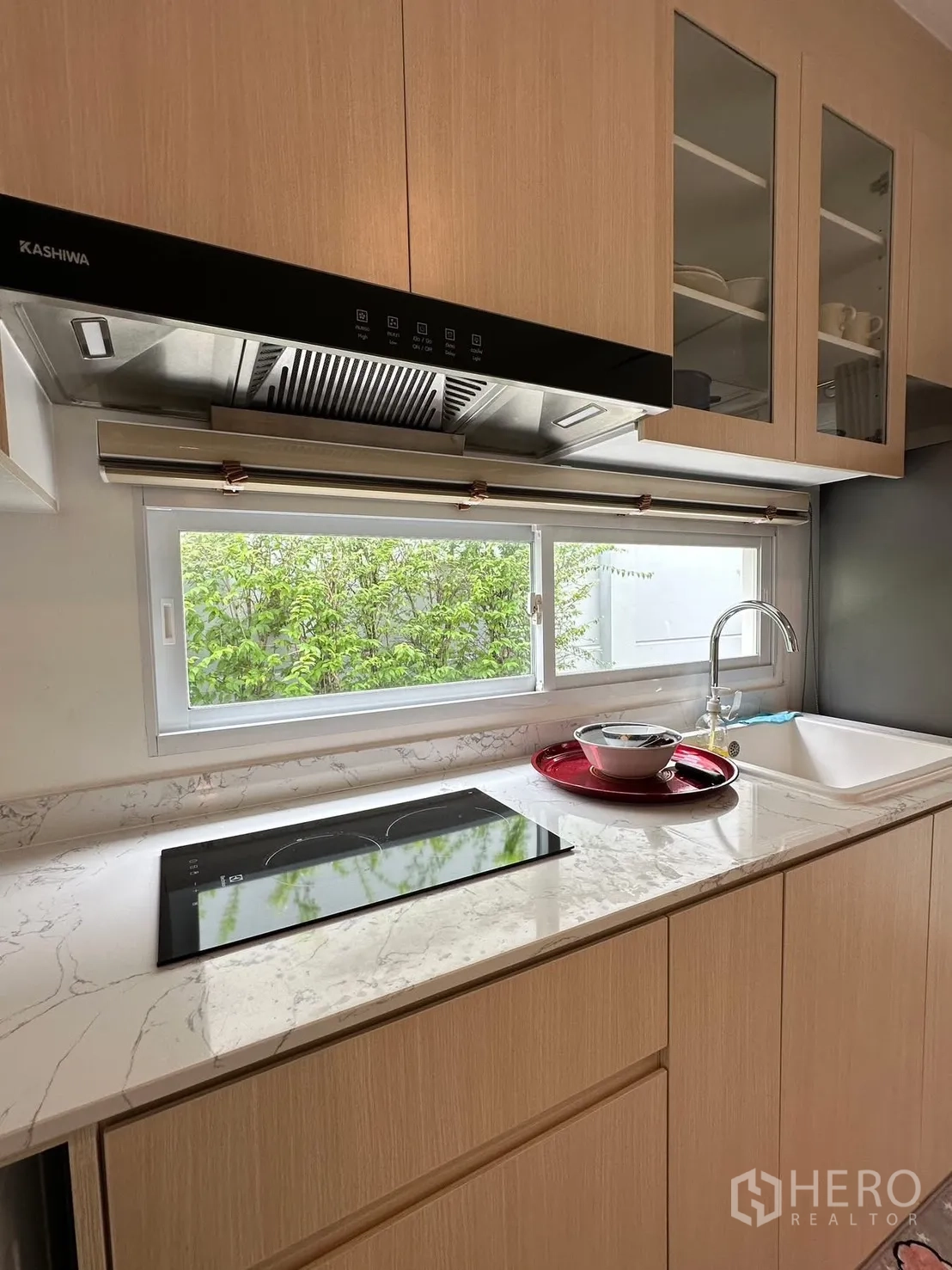 联排别墅 for rent in Prawet, Bangkok - 现代厨房，设大理石纹台面、电磁灶、油烟机与窗下水槽。