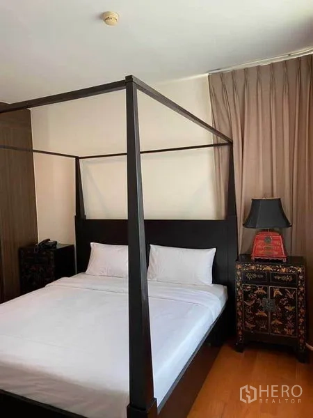 Condominium for rent in Watthana, Bangkok - Master bedroom with dark wood four-poster bed, bedside tables, and floor-to-ceiling curtains.