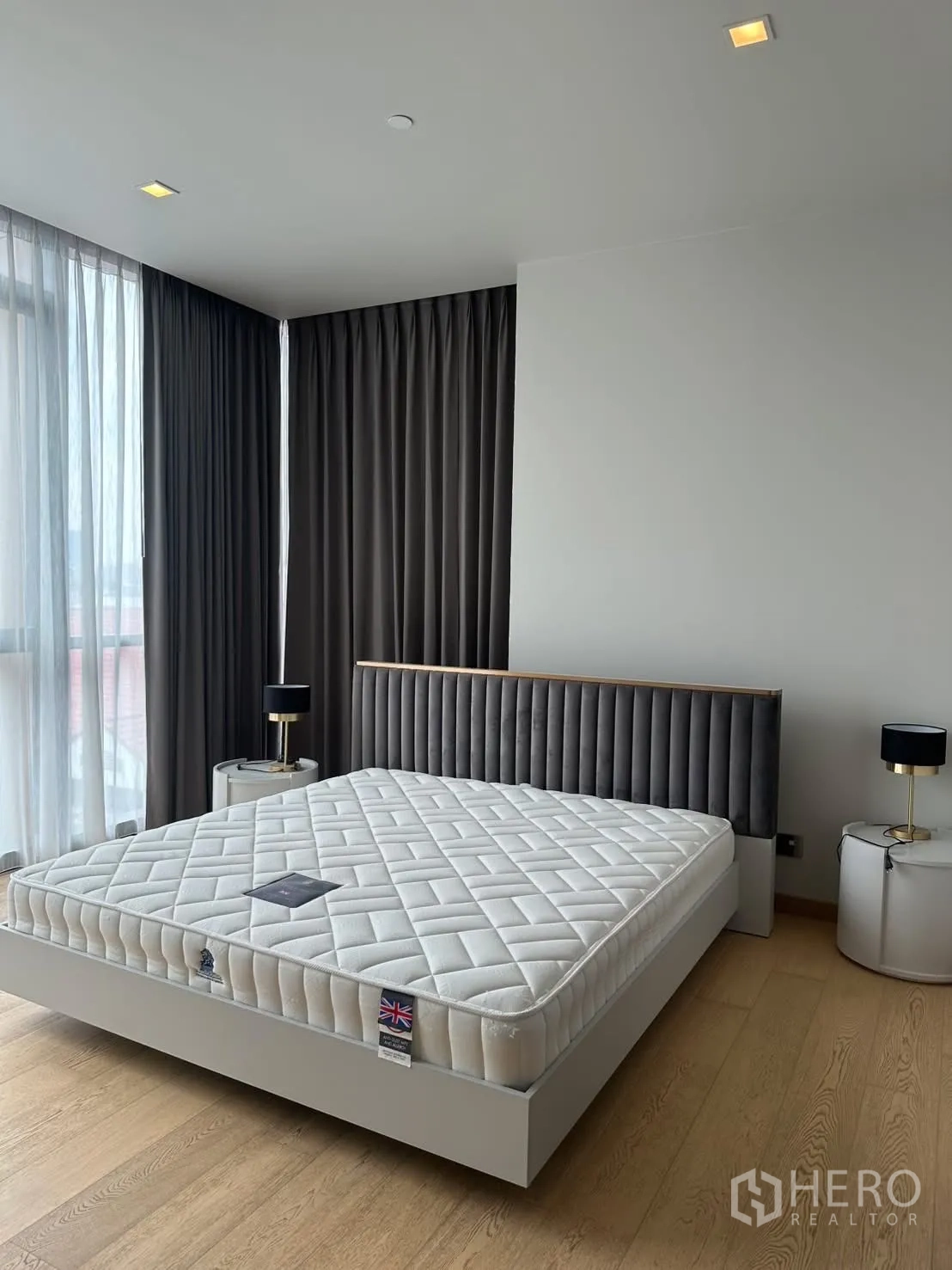Condominium for rent or sale in Watthana, Bangkok - Master bedroom with king bed, side tables, and large corner windows.