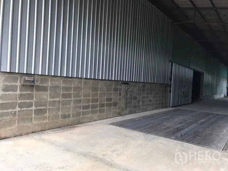 货栈 出租在Mueang Nakhon Pathom, Nakhon Pathom - 金属墙面旁的有顶装卸平台，配宽幅推拉门