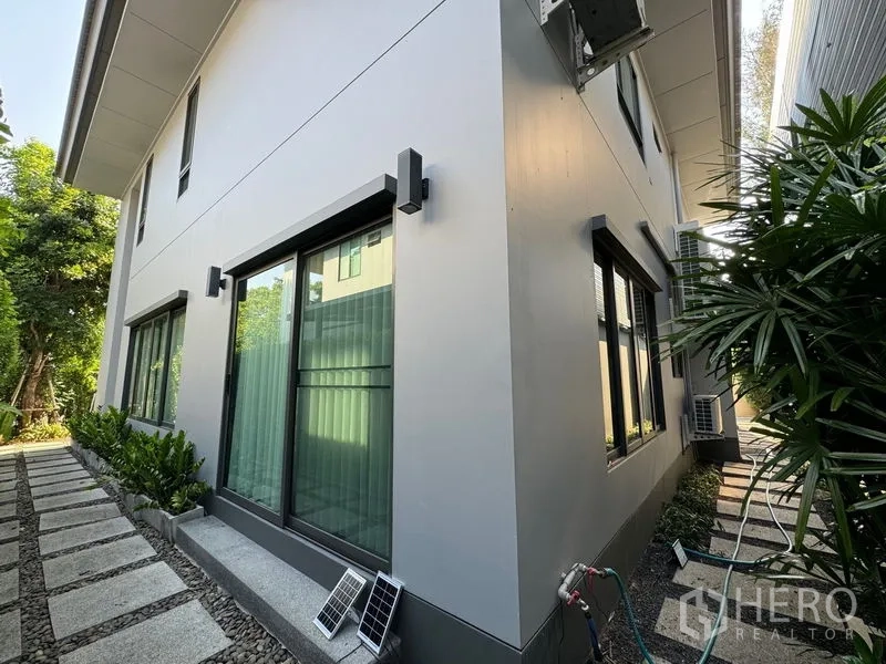 Detached House for rent in Bang Kapi, Bangkok - Rear corner of the home with sliding windows and a stone path around the building.
