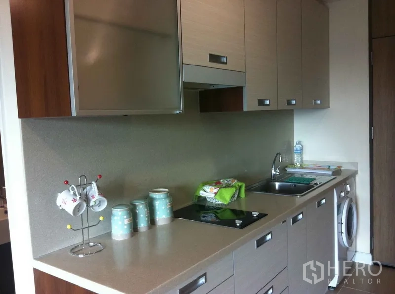 คอนโด ให้เช่าในKhlong Toei, Bangkok - ครัวแบบแกลลีย์ทันสมัย มีตู้แขวน เตาไฟฟ้า อ่างล้างจาน และเครื่องซักผ้าในห้อง