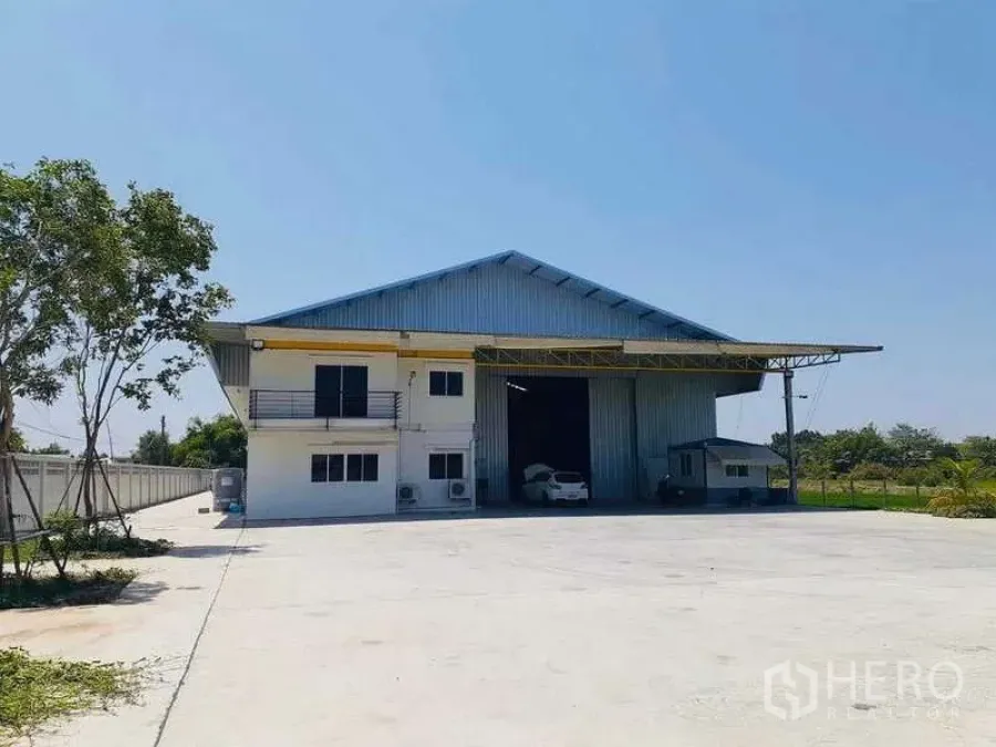 คลังสินค้า ขายในSai Noi, Nonthaburi - ด้านหน้าโกดังและอาคารสำนักงาน พร้อมทางเข้าและลานจอดคอนกรีตกว้าง