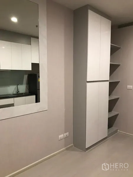 Condominium for rent in Pathum Wan, Bangkok - Built-in tall cabinet and open corner shelves in a neutral-toned room