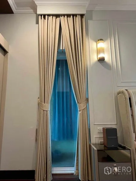 Detached House for sale in Bueng Kum, Bangkok - Detail of tall curtains and a wall light beside the bed in a serene bedroom.