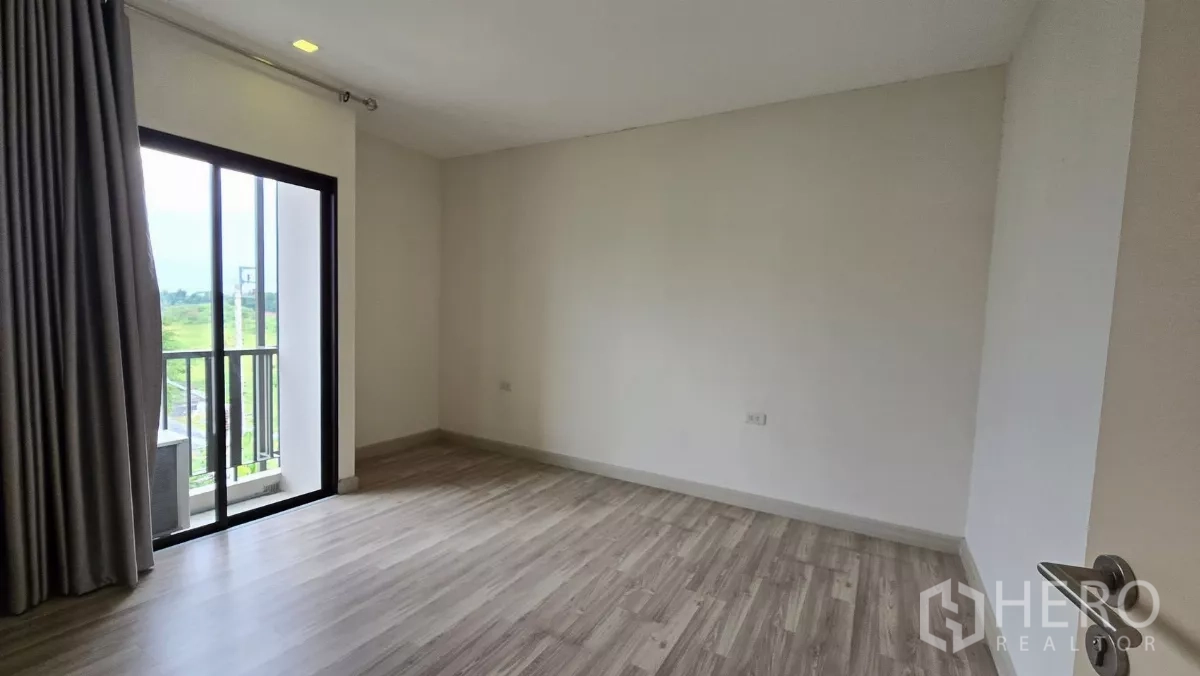 Townhouse for rent or sale in Saphan Sung, Bangkok - Bedroom with sliding doors opening to a small balcony and greenery.