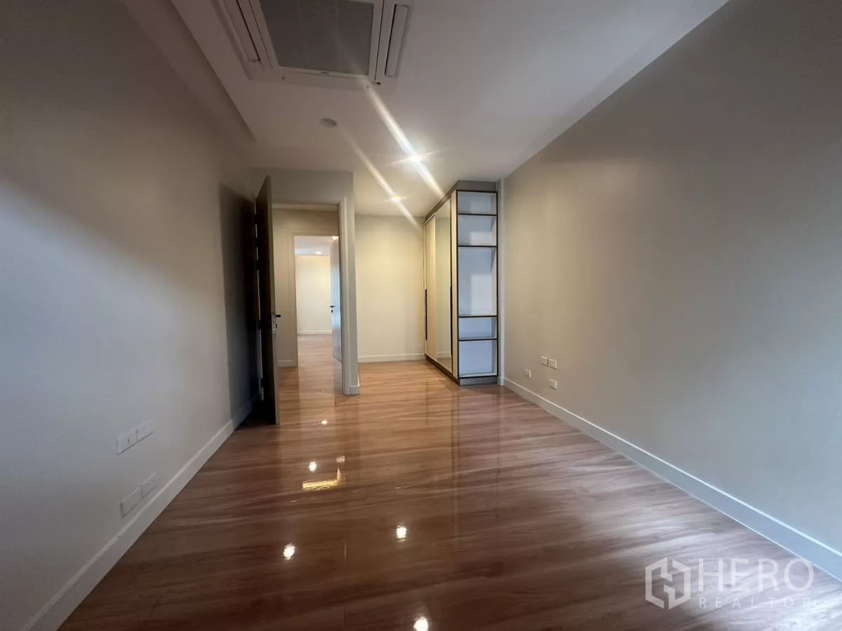 Townhouse for rent in Watthana, Bangkok - Long bedroom view with built-in wardrobe and warm cove lighting.