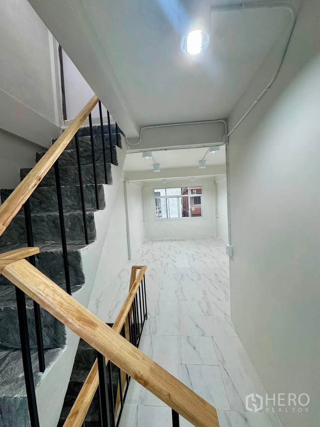 Shophouse for rent in Sathon, Bangkok - Stairwell with wood handrail overlooking a bright room.