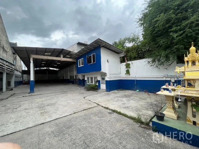 Warehouse for rent in Phra Khanong, Bangkok - Central courtyard with covered loading area, two-storey office building, and spirit house.