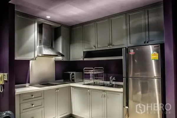 公寓 出租或出售在Khlong Toei, Bangkok - 现代L形厨房，灰色橱柜，抽油烟机与不锈钢冰箱。