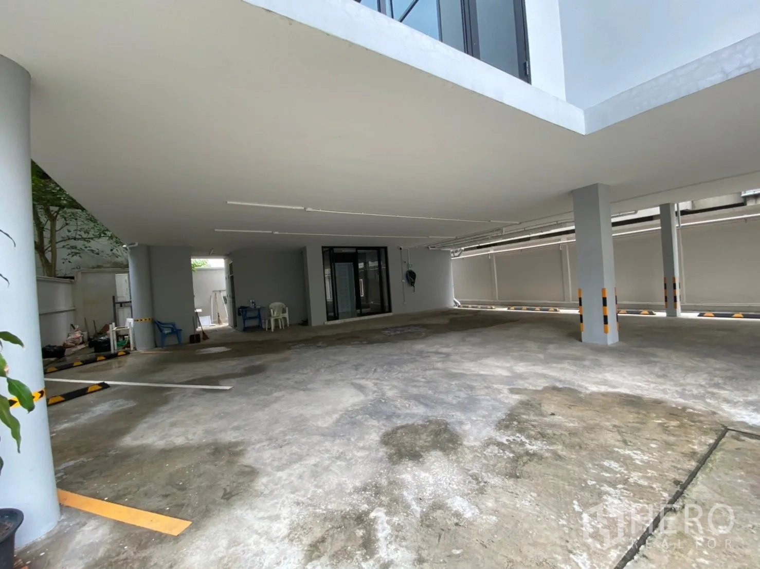 Home Office for rent or sale in Watthana, Bangkok - Covered parking area beneath the building with multiple marked spaces.