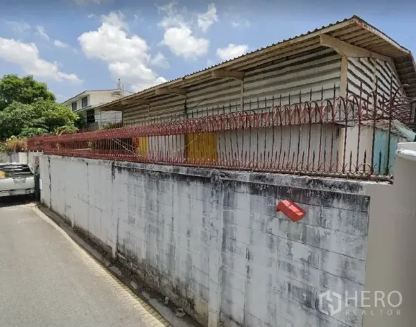 Warehouse for rent in Bang Sue, Bangkok - Street view of low-rise warehouse behind secure wall and barbed fence in Bang Sue.