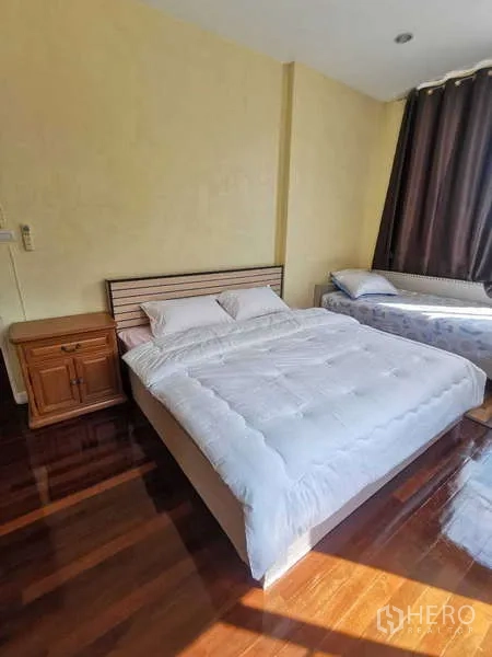 ทาวน์เฮาส์ ให้เช่าในChatuchak, Bangkok - ห้องนอนเตียงคู่ มีตู้ข้างเตียง และเตียงเดี่ยวเสริมข้างหน้าต่าง.