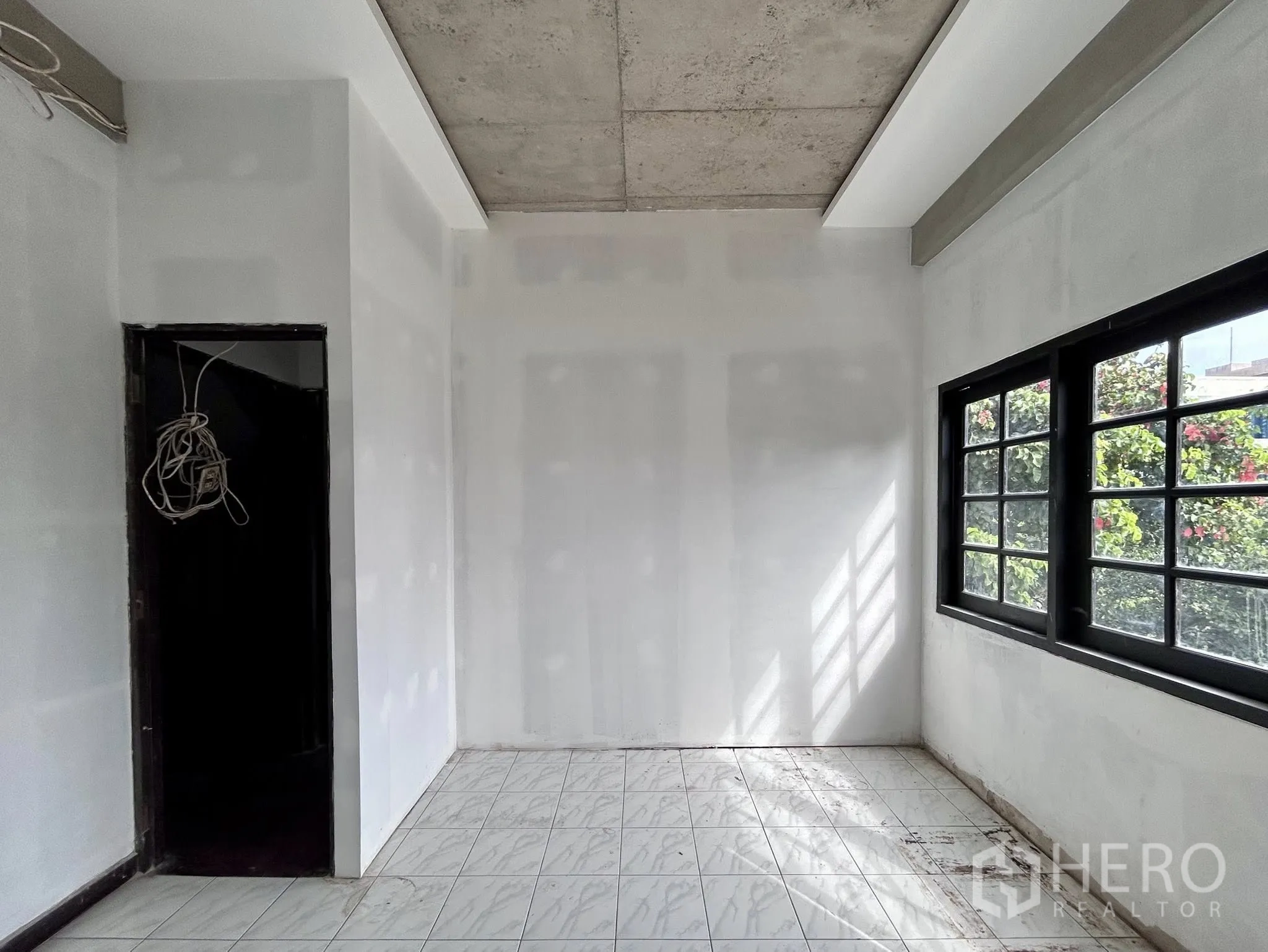 家庭办公室 for rent or sale in Watthana, Bangkok - 采光明亮的小房间，瓷砖地面、白墙与黑框窗户。
