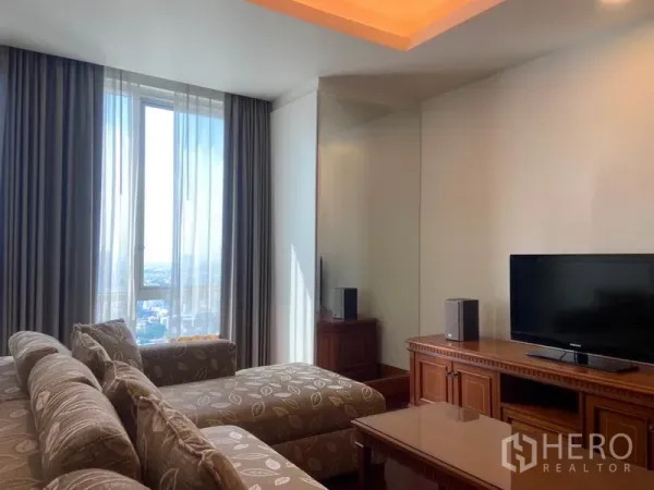 公寓 出租在Sathon, Bangkok - 明亮起居室，电视柜与镜面墙，落地窗可望城市天际线。