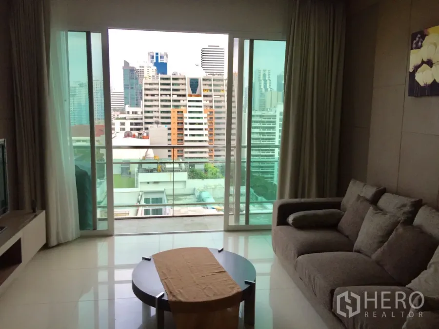 Condominium for rent in Watthana, Bangkok - Bright living room with sofa, coffee table and sliding doors opening to a balcony with Bangkok city views.