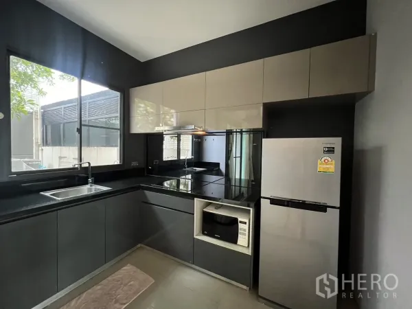 联排别墅 出租在Lat Phrao, Bangkok - 現代L型廚房，帶窗與整體櫥櫃，電磁爐、烤箱與不鏽鋼冰箱。