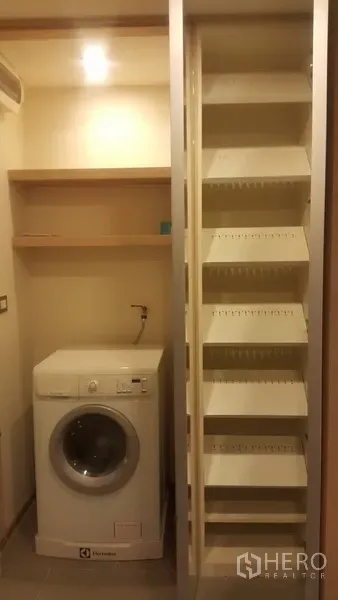 公寓 出租在Ratchathewi, Bangkok - 洗衣间配前开式洗衣机、置物架和可拉出式储物层架。