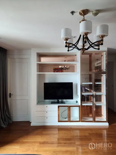 公寓 出租在Bang Rak, Bangkok - 客厅设有电视与展示柜一体的壁柜、吊灯和光亮木地板。