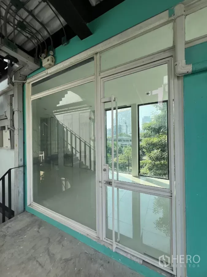 零售空间 出租在Watthana, Bangkok - 三楼零售门面，玻璃大门与青绿色外墙，配楼梯出入并可眺望绿景。