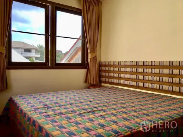 Detached House for rent in Khlong Toei, Bangkok - Bright bedroom with large windows, curtains and a cushioned headboard.