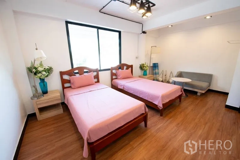 带办公室的家 出租或出售在Phra Khanong, Bangkok - 宽敞双床卧室，粉色床品、沙发与木地板。